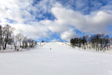 Sabahları kayak yapan birkaç kayakçıyla kayak pistinde güzel kış manzarası olan bir bayır.