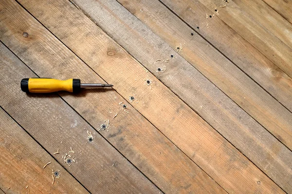 修理木制地板 螺丝刀和许多固定螺丝顶部视图特写行 — 图库照片