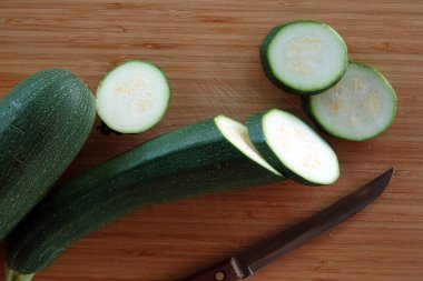 Olgun, yuvarlak, dilimlenmiş kabak parçaları kahverengi ahşap mutfak tahtasının üstüne uzanır.