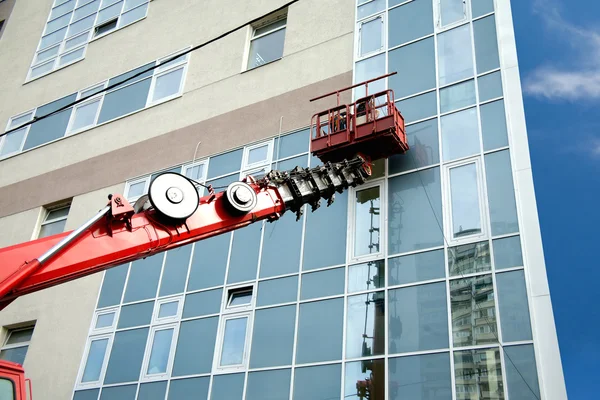 Red construction crane boom in process of finishing office building — Stock Photo, Image