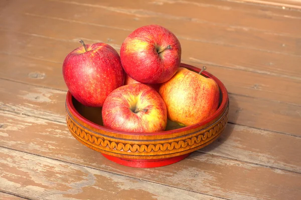 Спелые красные и желтые яблоки в деревянной чаше крупным планом — стоковое фото
