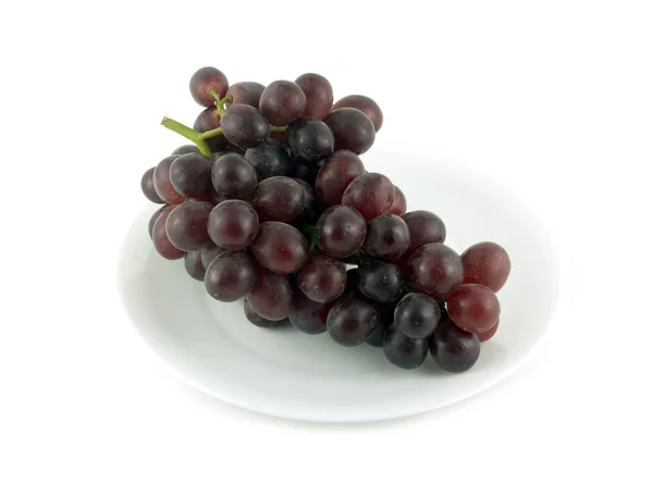 Ramo de uva vermelha na placa isolado sobre branco de perto — Fotografia de Stock