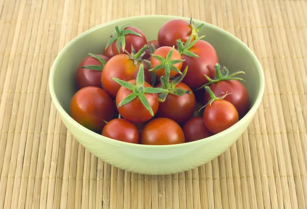 Tomates rouges dans un bol vert sur un tapis de paille — Photo