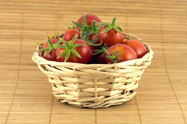 Tomates rouges dans un panier en osier sur un tapis de paille — Photo
