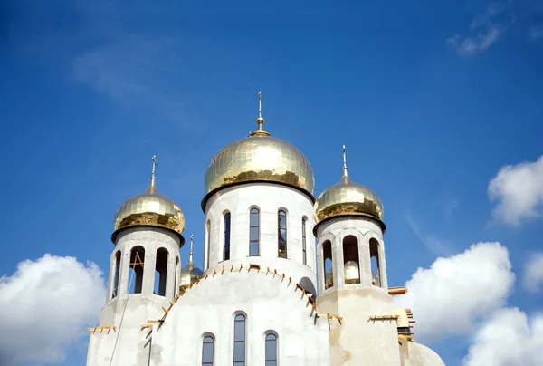 Construcción de un nuevo templo con cúpulas de oro contra el cielo azul —  Fotos de Stock