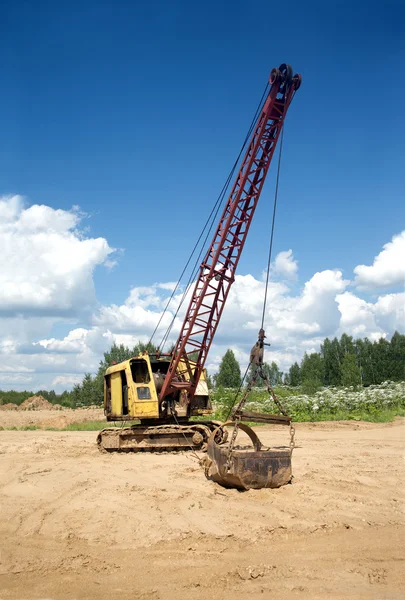 Excavadora de pie en la arena cerca del bosque en el día de verano —  Fotos de Stock