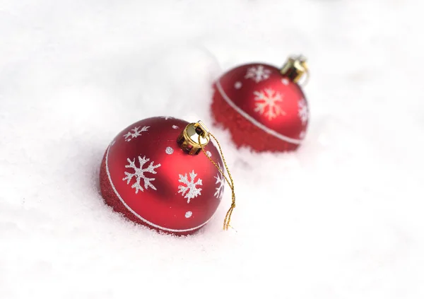 Red Christmas balls with painted snowflakes lying on white snow — Stock Photo, Image