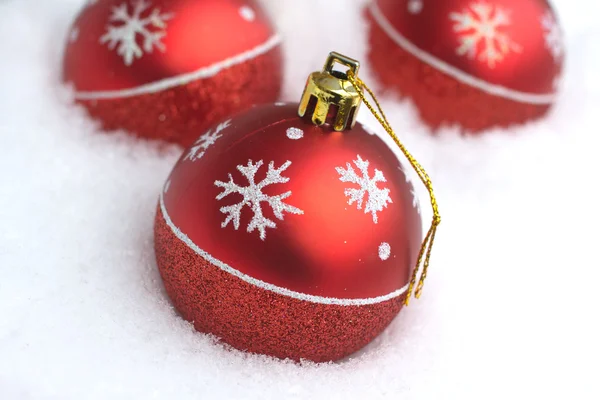 Red Christmas balls with painted snowflakes lying in clean white snow — Stock Photo, Image