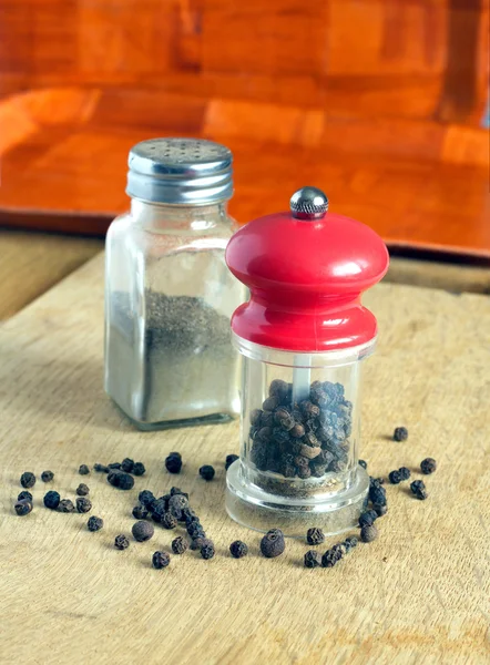 Pepper, pepper mill and spice jar on kitchen desk closeup — Stock Photo, Image