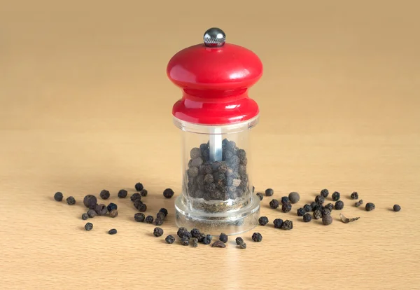 Zwarte peper en handmatige molen op hout — Stockfoto