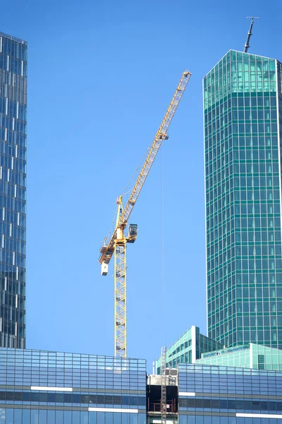 Tower crane on top of construction office skyscraper buildings over blue sky — Stock Photo, Image