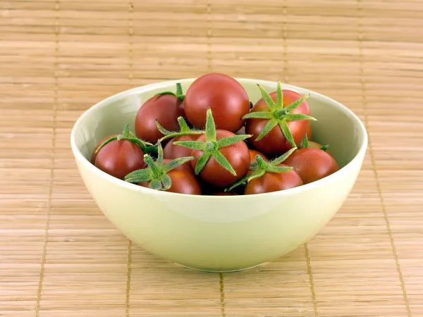 Tomates rouges dans un bol vert sur un tapis de paille — Photo