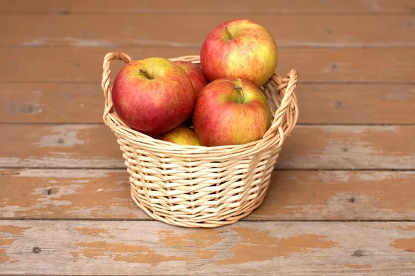 Manzanas en canasta de mimbre marrón claro en primer plano escritorio de madera vieja —  Fotos de Stock