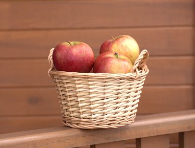 Ahşap çit üzerinde hafif kahverengi hasır sepet elma