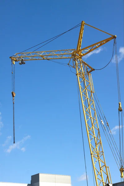 Баштовий кран на промисловому будівництві над синім небом — стокове фото
