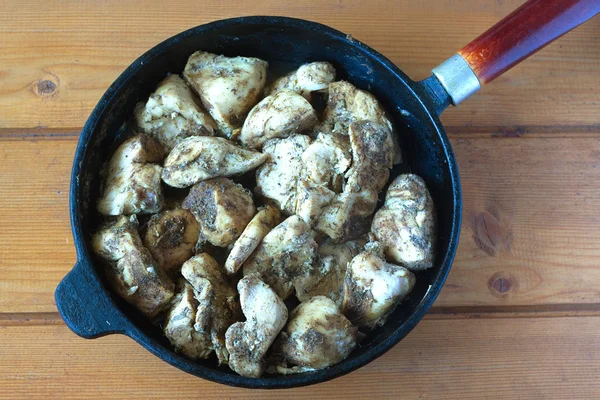 Жареная курица с ароматическими специями на черной сковороде — стоковое фото