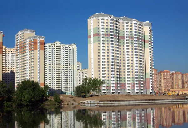 Nieuwe gebouwen over rivier en heldere blauwe hemel in zomerdag — Stockfoto