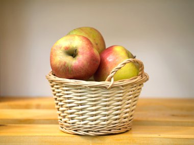 Bir raf üzerinde hafif kahverengi hasır sepet elma