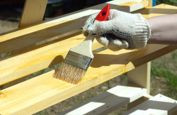 Female hand in textile glove paint wooden shelving — Stock Photo, Image