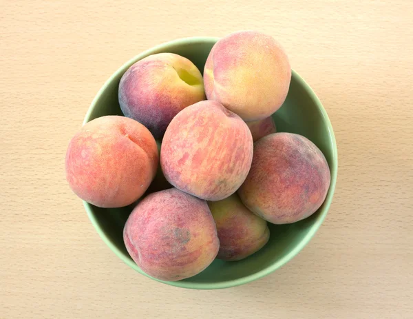 Peaches in green bowl top view — Stok fotoğraf
