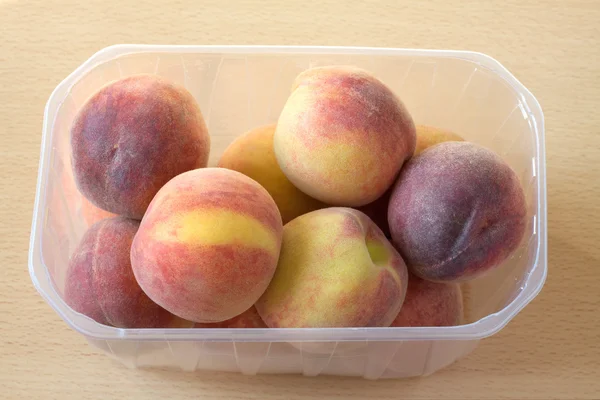 Персики в пластиковій тарі вид зверху — стокове фото