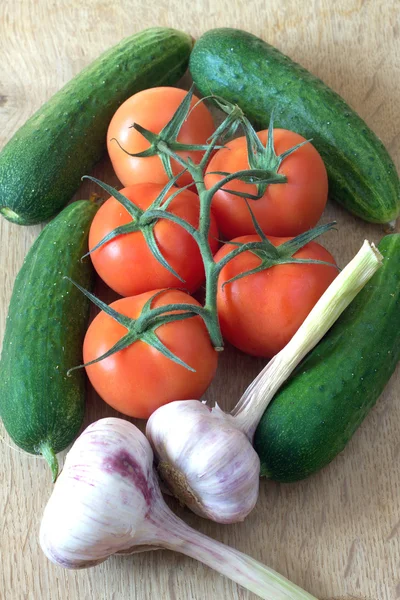 Tomates, pepinos y ajo sobre fondo de madera —  Fotos de Stock