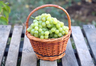 Ahşap masa portre üzerinde kahverengi hasır sepet üzüm