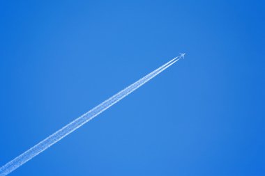 Passenger jet flying in clear blue sky, leaving white trail clipart