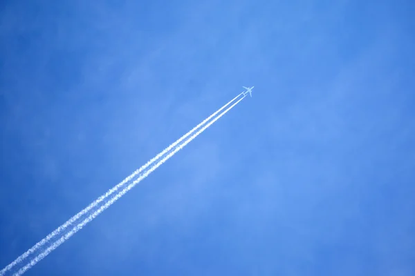Avión de pasajeros volando en cielo azul claro, dejando rastro blanco — Foto de Stock