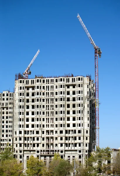 Hoisting tower cranes and top of construction buildings — Stock Photo, Image