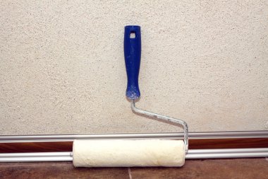 Süpürgelik duvarının yakınında bir oda boya silindiri duruyor