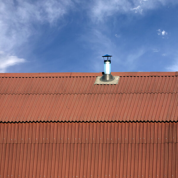 Gable roof of a house covered with metal tile with smoke pipe closeup