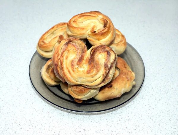 Tasty baked buns on the plates on the table in kitchen — Stock Photo, Image