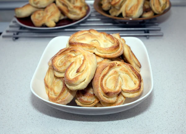 Tasty bakat bullar på tallrikar på bordet i köket — Stockfoto