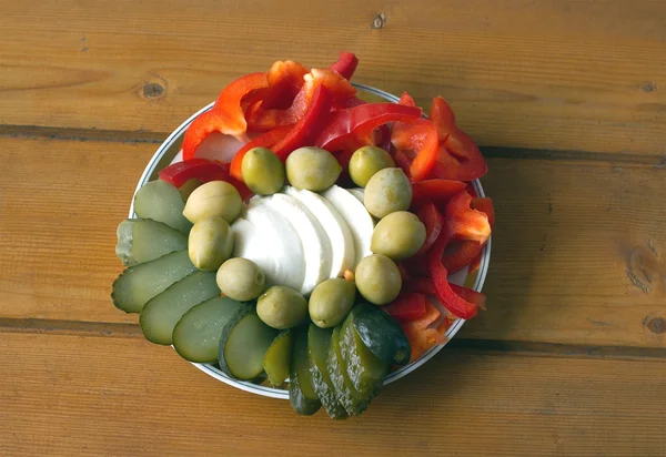 Naturaleza muerta con verduras frescas y encurtidas en el plato sobre una superficie de madera —  Fotos de Stock