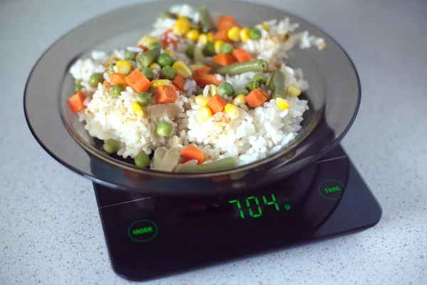 stock image Plate with rise and vegetables on kitchen scales closeup