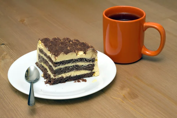 Piece of sponge cake on a plate and cup of tea close-up — Stock Photo, Image