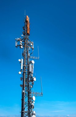 Telekomünikasyon kulesi 5G, 4G ve 3G cep telefonu sinyalleri gönderiyor. Yüksek hızlı mobil ağ ve geniş bant internetin dijital antenleri ve ekipmanlarıyla verici direği.