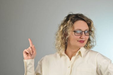 Sarı saçlı, beyaz bluzlu, gözlüklü genç bir kadın.