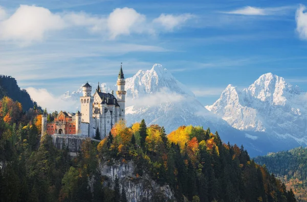 Tyskland. Den berömda slottet Neuschwanstein i bakgrunden av snötäckta berg och träd med gula och gröna blad. — Stockfoto