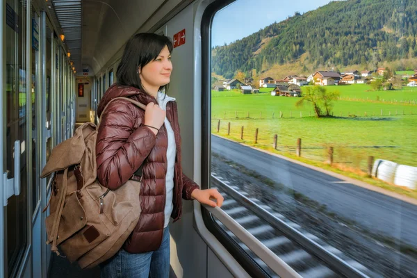  Hareket eden bir trenin penceresinden yakınındaki bir sırt çantası konumu olan kız. Güzel görünüm penceresinde.