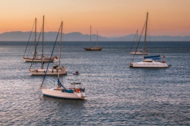 Sailboats at sunset in the Mediterranean Sea off the coast of Mandraki harbor. Rhodes Island. Greece.