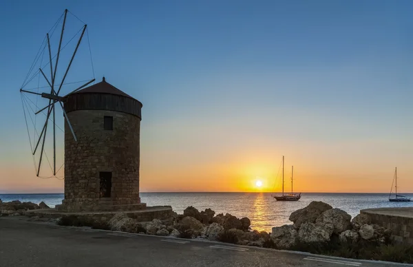 Mill on the background of the rising sun in the harbor of Mandraki. Rhodes Island. Greece — Stok fotoğraf