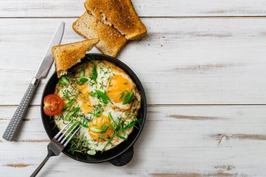 Çırpılmış yumurta, yeşil lahanalı ve yeşil soğanlı ahşap arka planda bir tavada..