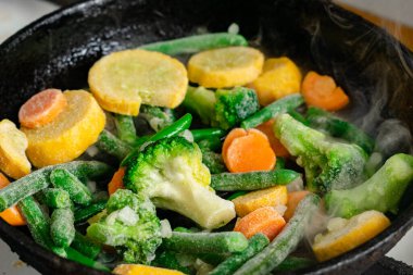 Tavada dondurulmuş sebzeler. Farklı sebzelerin karışımı - havuç, yeşil fasulye, karnabahar.