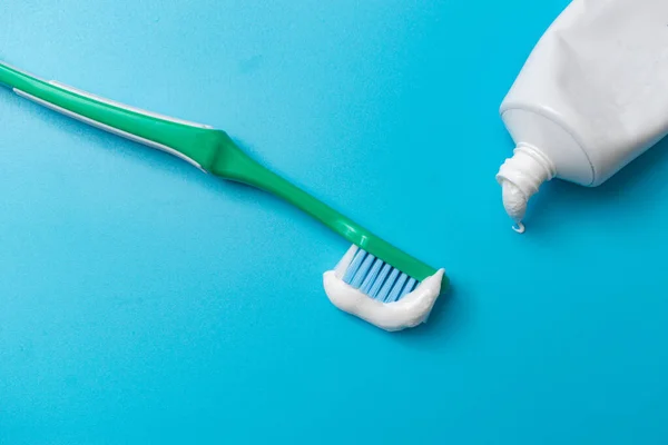 Toothbrush and toothpaste on a blue background. Dental hygiene concept.