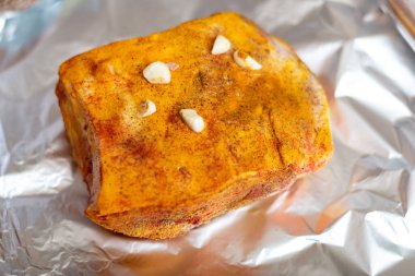 Baharatlı domuz pastası. Folyoda tuz, biber ve sarımsak rendelenmiş et..