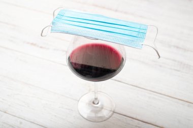Bir bardak şarap ve tıbbi maske. Koronavirüs konseptini kilitle.
