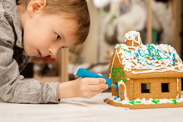 Ein Junge Schmückt Ein Lebkuchenhaus Vorbereitung Auf Weihnachten Neujahr — Stockfoto