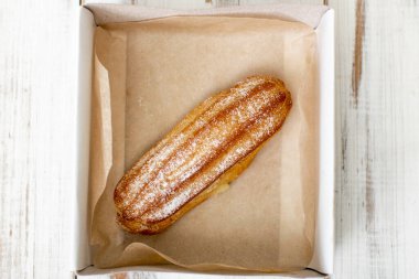 Beyaz ahşap arka plandaki bir kutuda kremalı pasta..